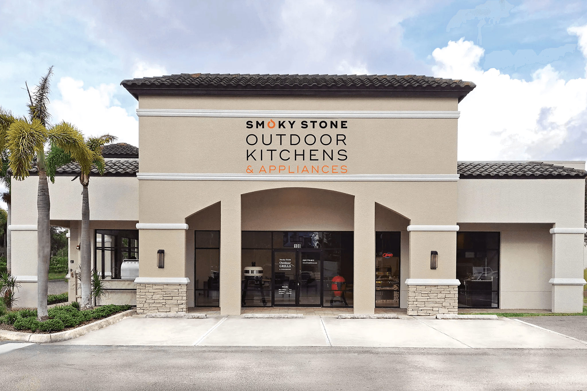 Smoky Stone Outdoor Kitchens & Appliances showroom exterior with palm trees and outdoor grills visible inside.