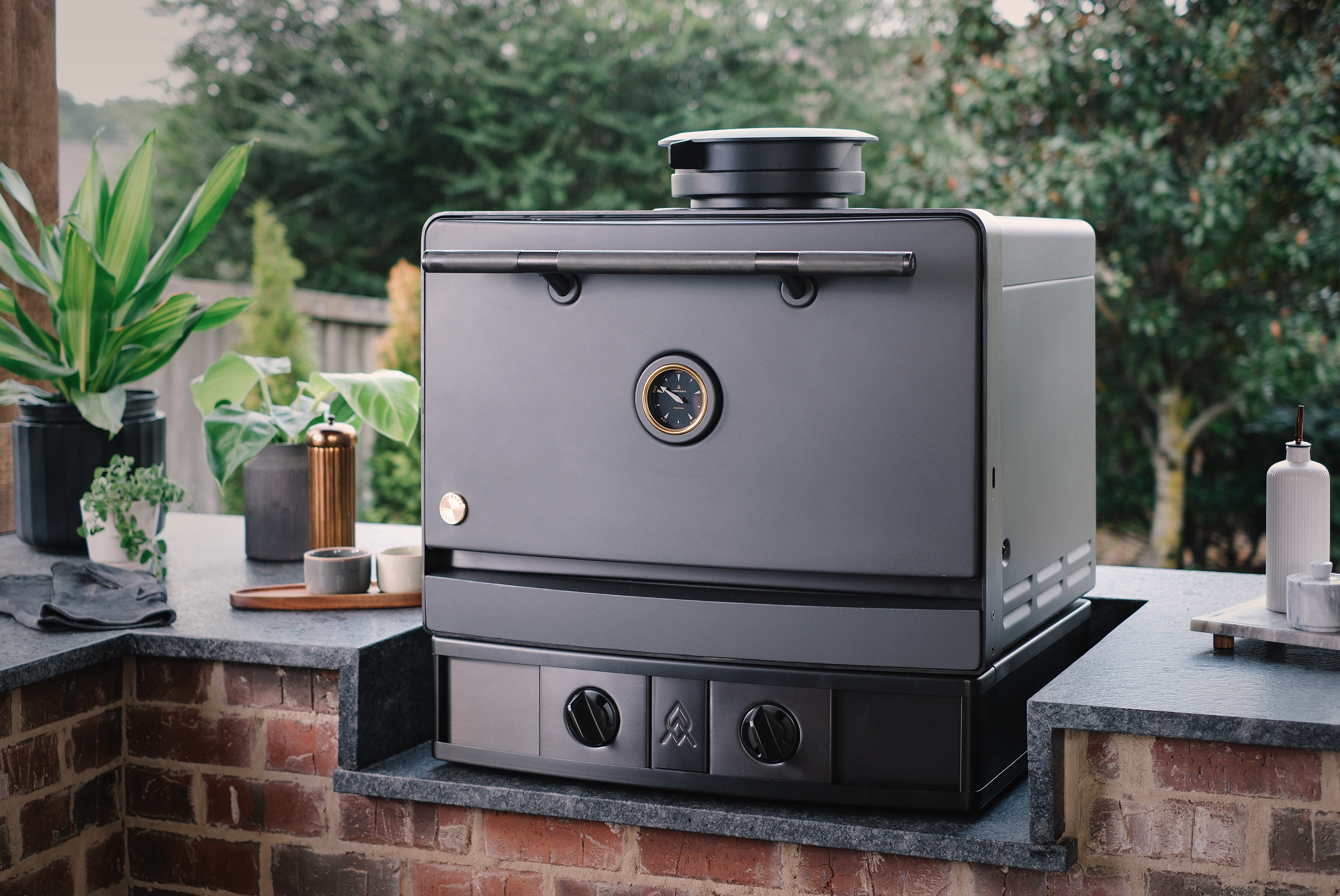 Emberhaus Fire Oven in Iron color installed in a luxury outdoor kitchen, showcasing its modern design, precision temperature gauge, and premium craftsmanship.
