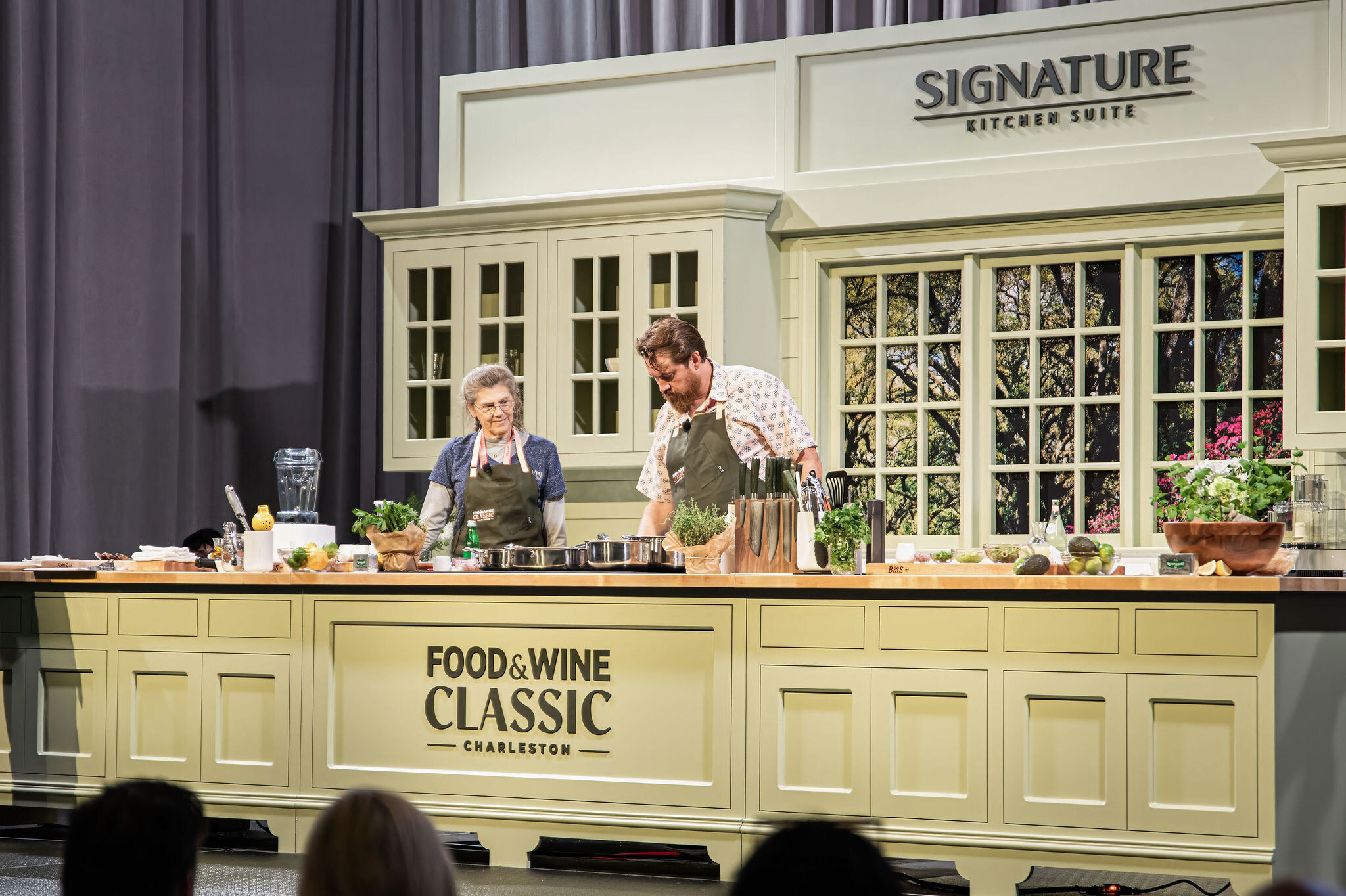 Chefs cooking on stage at the Food & Wine Classic in Charleston, presented by Signature Kitchen Suite, showcasing premium kitchen appliances and culinary craftsmanship.